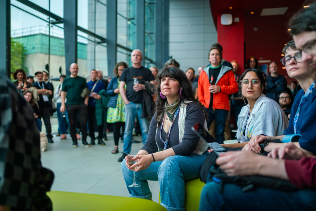 An audience sits and listens to a talk at a conference
